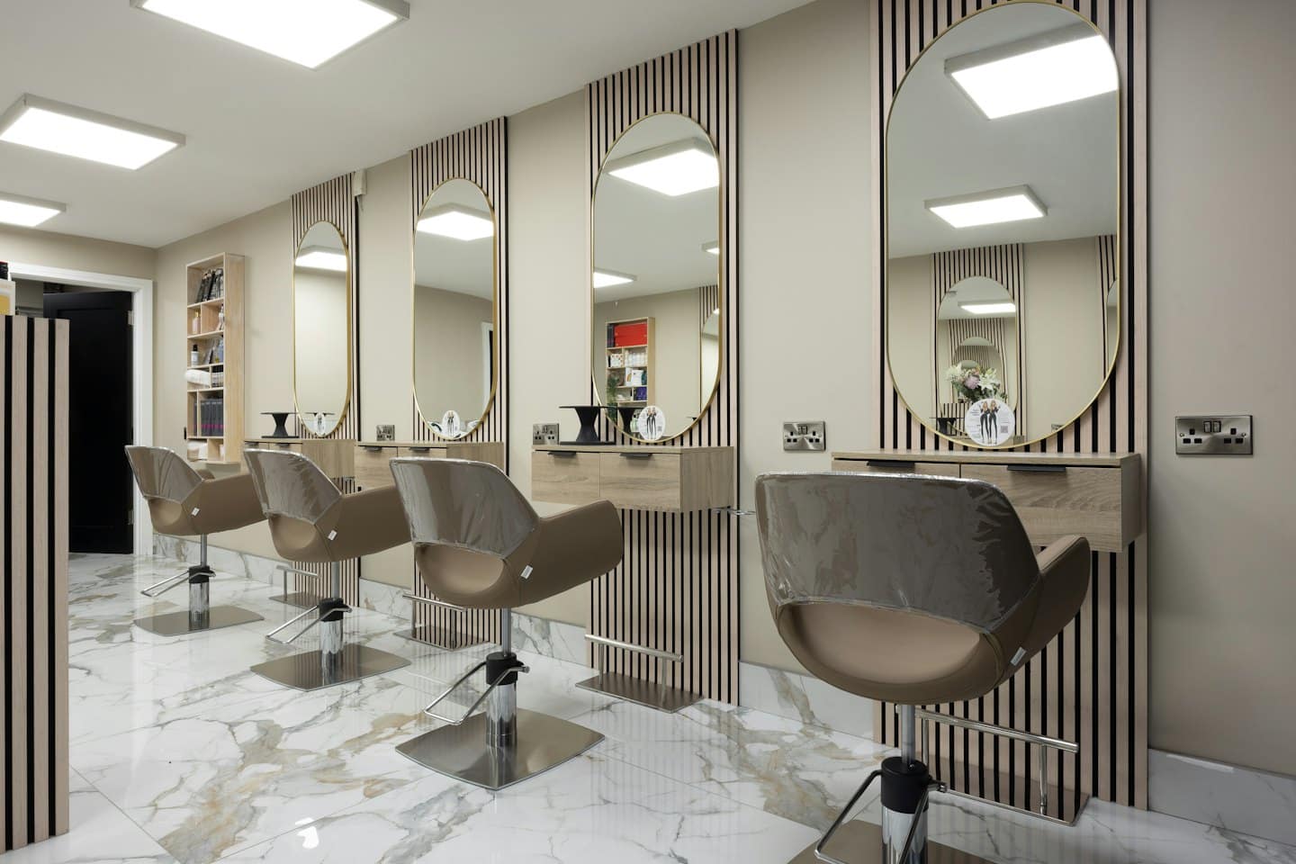 Leerer moderner Friseursalon mit Frisierplätzen und Marmorboden.